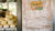 Melons at a farm stand with an old wooden door and sign giving the times open for business. 