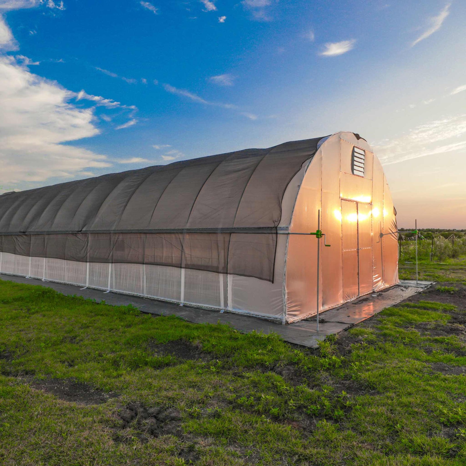 Side view of a 20-foot all-metal round hoop house with roll-up sides and a high-strength plastic cover. The robust structure is designed to maximize airflow and provide efficient temperature control, crafted in the USA for superior quality.