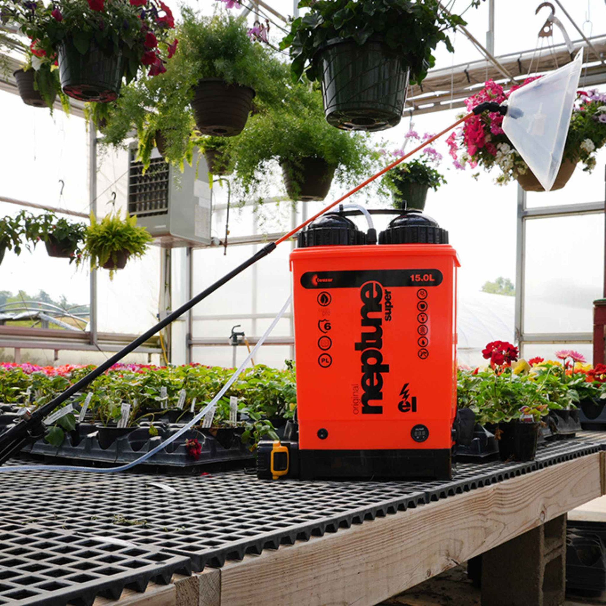 Neptune 15L Electric Backpack sprayer with shield on greenhouse table with hanging baskets and nursery pots