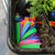 A collection of colorful plant labels (green, pink, purple, orange, and blue) placed in a tray filled with soil. Some are scattered on the soil while others are stacked neatly, highlighting the vibrant colors.